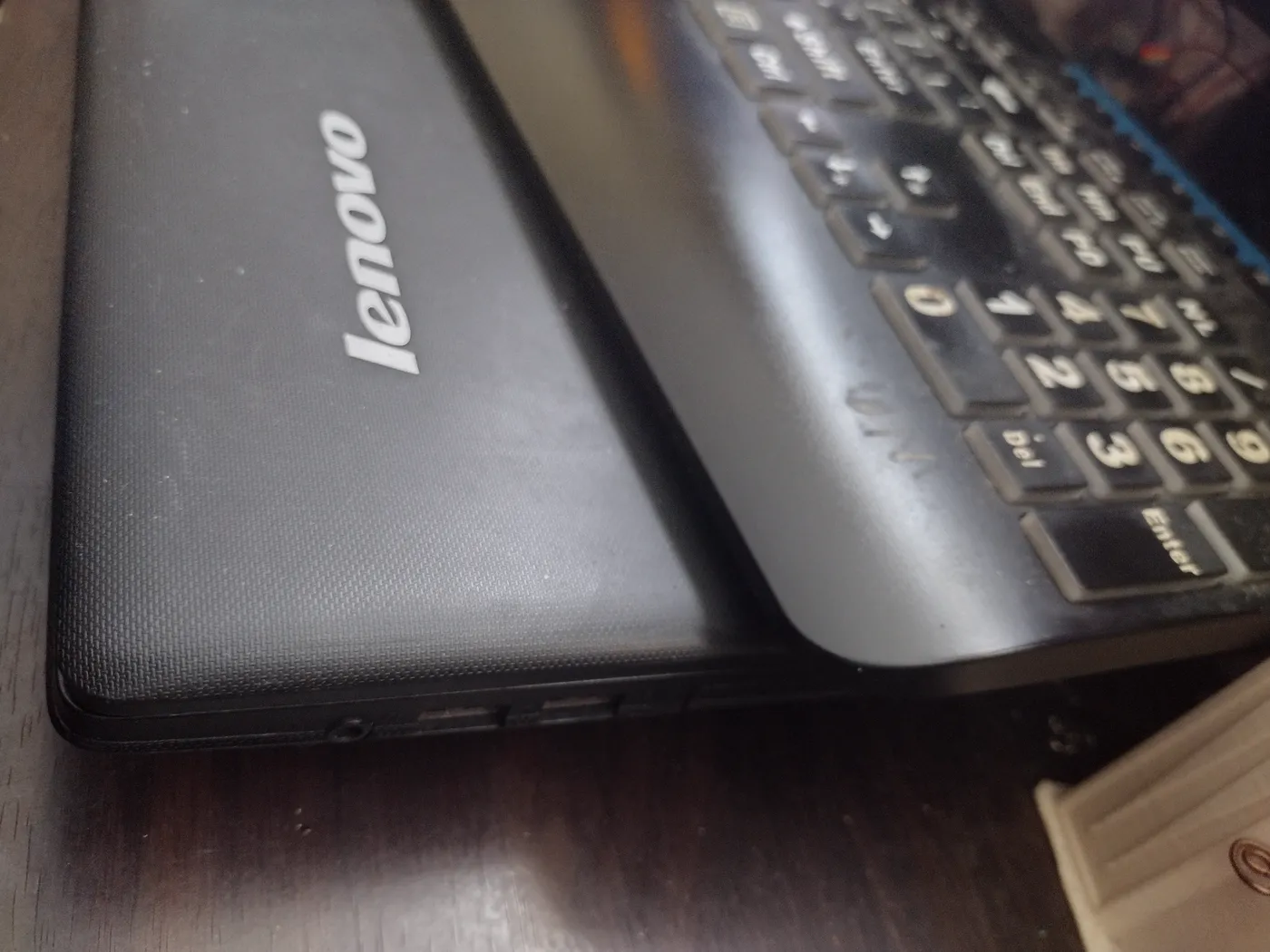 Close-up of the salvaged Lenovo G710 lid — Lenovo logo and number pad, on the desk.